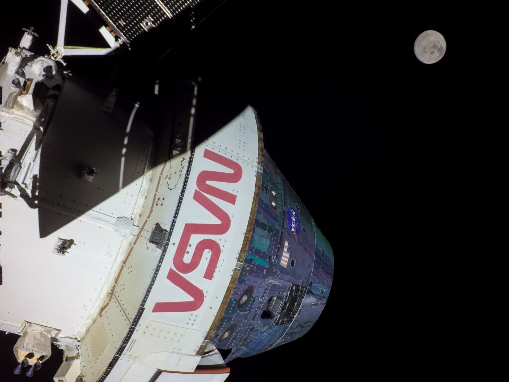Space capsule with "VSN" lettering angled in darkness, illuminated partially, against a backdrop of a bright full moon.