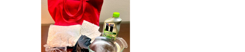 Red tote bag beside a silver bowl, black gloves, a clear package of material, and a green bottle of Mobil 1 engine oil on a brown surface.