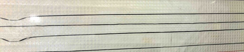 Close-up of layered textile with embedded black sensing lines on a light, textured background, showcasing smart textile technology.