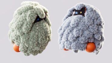 Two soft, textured robotic figures resembling fluffy creatures, one in green and the other in gray, with round orange bases and playful expressions.