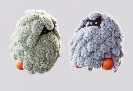 Two soft, textured robotic figures resembling fluffy creatures, one in green and the other in gray, with round orange bases and playful expressions.