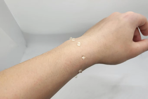 Clear wearable medical monitor attached to a wrist, featuring a sleek design with small, discrete nodes along a thin, flexible band.