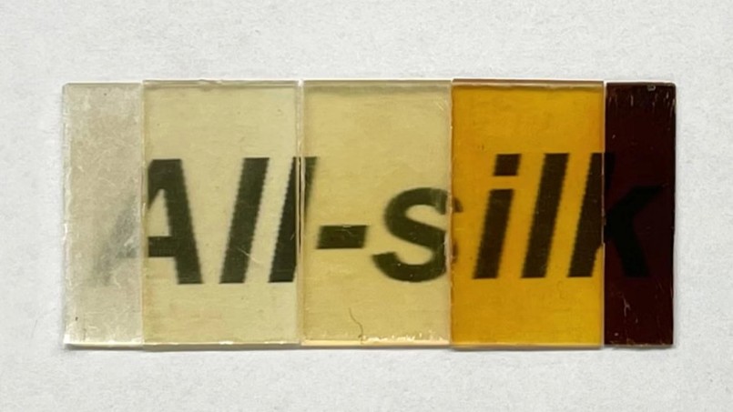 A series of translucent silk swatches in varying shades from light yellow to dark brown, showcasing different textures and finishes.