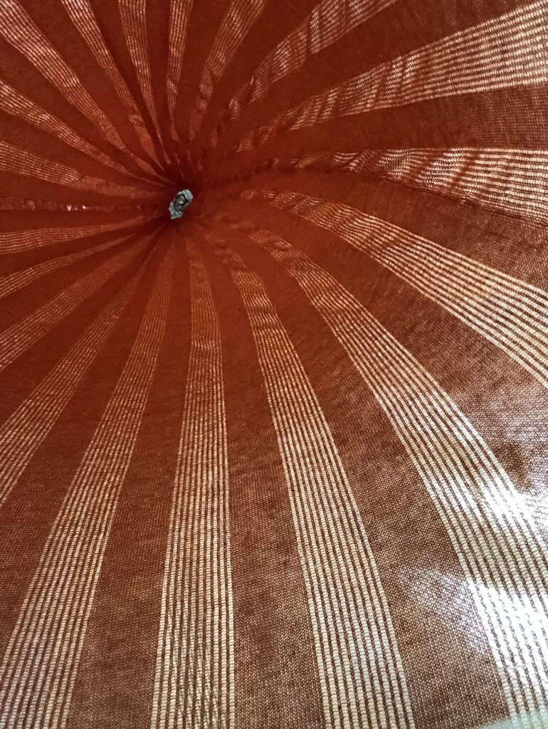 Red and white striped fabric stretching inward, creating a cone shape, with a central opening visible at the top.