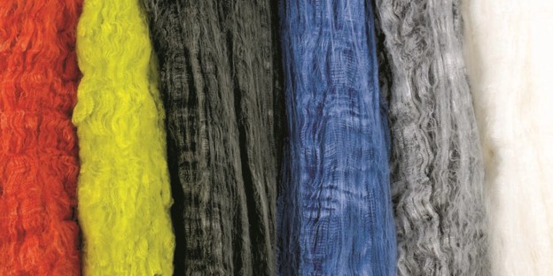 Strands of Nomex fiber displayed in assorted colors: red, yellow, black, blue, gray, and white, showcasing their textured surfaces.